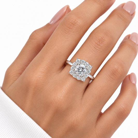 Crest sterling silver cushion halo ring worn on a hand with nude pink nails against white