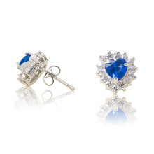 Load image into Gallery viewer, A beautiful tribute to the heart. Delicate rhodium plated studs with cubic zirconia stones framing a subtle blue heart stone at the centre. For pierced ears. Side view (Butterfly and pole closure)
