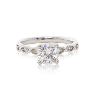 A delicate 925 sterling silver ring with a round brilliant cubic zirconia centre stone with ornate entwined cubic zirconia stone embedded shoulders.